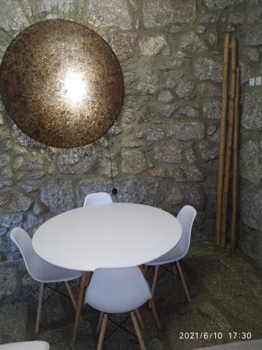 a white table and chairs in front of a stone wall at Casa das Andorinhas in Póvoa de Lanhoso