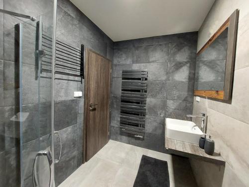 La salle de bains est pourvue d'un lavabo et d'une douche. dans l'établissement Apartmán Rezidence Javor Železná Ruda, à Železná Ruda