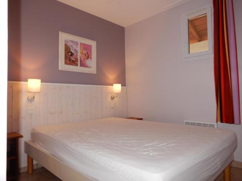 - une chambre avec un lit blanc et deux lumières sur le mur dans l'établissement Appartement au Domaine du Golf dans résidence de vacance, à Moliets-et-Maa