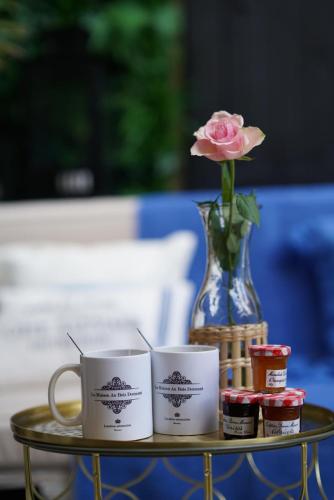 a table with two cups and a rose in a vase at Fabuleux! La Maison Au Bois Dormant in Barraux