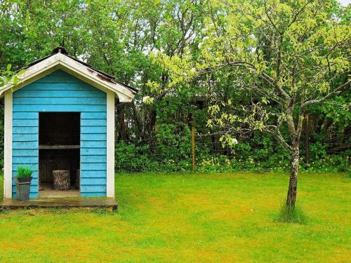 niebieski domek dla psów na podwórku z drzewem w obiekcie 8 person holiday home in HOVA w mieście Hova