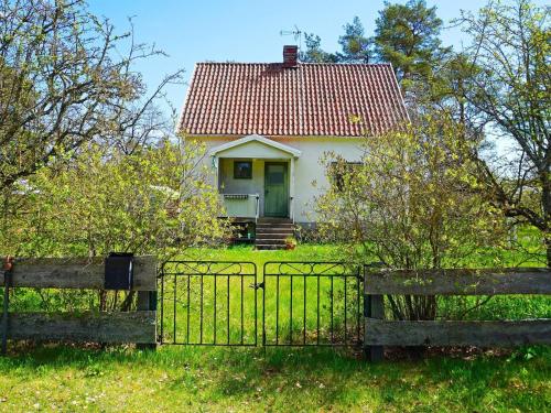 una pequeña casa blanca con una puerta verde detrás de una valla en 4 person holiday home in ST NGA, en Stånga