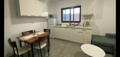 uma pequena cozinha com uma mesa e cadeiras numa cozinha em אירוח אריאל em Hagoshrim