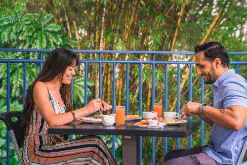 Ein Mann und eine Frau sitzen am Tisch und essen Essen. in der Unterkunft Hotel Monte Real in Fortuna