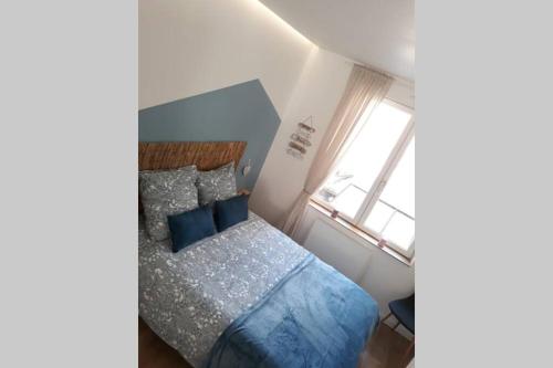 une chambre avec un lit bleu et une fenêtre dans l'établissement La Canisse 1 - Joli appartement - Boulogne-sur-mer, à Boulogne-sur-Mer