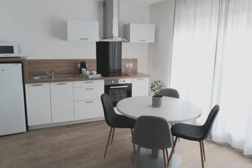 une cuisine avec une table et des chaises dans une cuisine dans l'établissement La Canisse 1 - Joli appartement - Boulogne-sur-mer, à Boulogne-sur-Mer