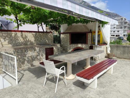 a picnic table and a bench and a pizza oven at Villa Radić in Makarska