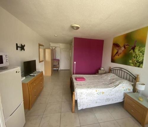 - une chambre avec un lit et un mur violet dans l'établissement Studio à la semaine, au mois ou plus, à Le Moule