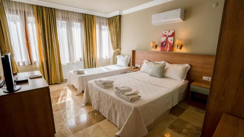 Cette chambre comprend deux lits et une télévision. dans l'établissement Ebruli Hotel Cunda, à Ayvalık
