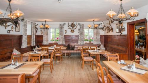 a restaurant with wooden tables and chairs and windows at Sport & Familienhotel Bärenwirt in Aich