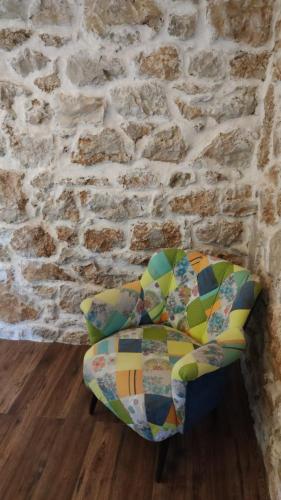 a colorful chair sitting in front of a brick wall at Stone hause Noa in Rab