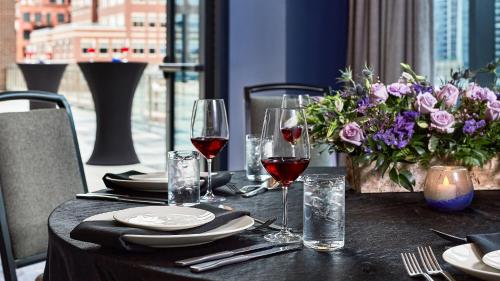 a table with glasses of wine and a vase of flowers at The Rally Hotel at McGregor Square in Denver