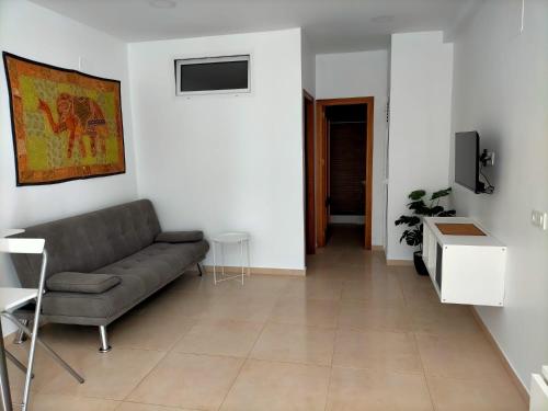 een woonkamer met een bank en een tv bij Apartamento avenida de la musica in Conil de la Frontera
