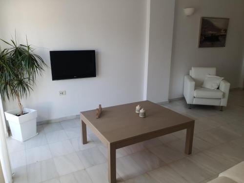 a living room with a table and a tv on a wall at Elizabeth Suites in Kato Daratso