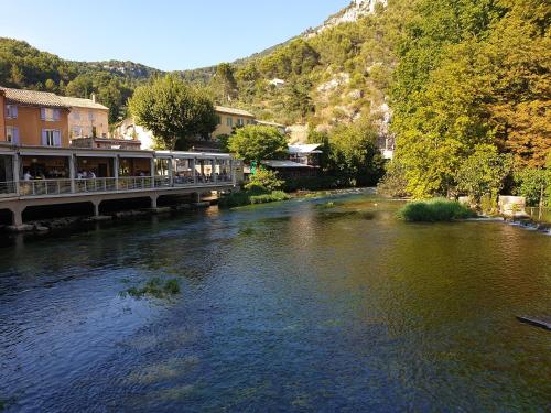 eine Brücke über einen Fluss in einer Stadt mit Gebäuden in der Unterkunft Atelier n°4 in Fontaine-de-Vaucluse