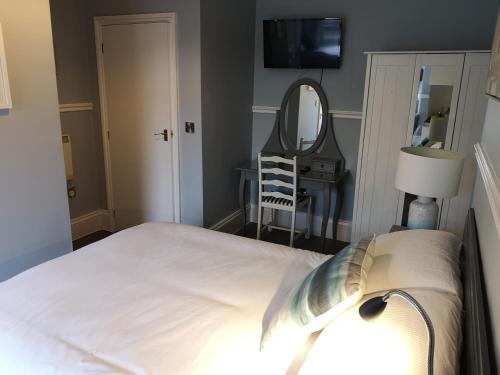 a bedroom with a bed and a mirror and a table at The Sunfold in Weston-super-Mare