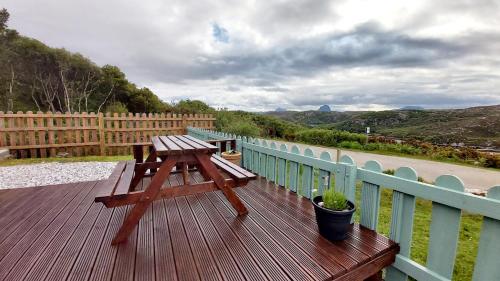 a wooden deck with a picnic table on a fence at Achmelvich View self catering in Lochinver