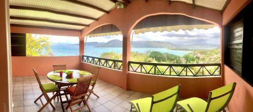 a balcony with a table and chairs and a view of the ocean at Habitation Bellevue in Sainte-Anne