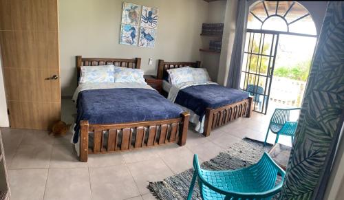 two beds in a room with chairs and a window at Sarah's Place San Andres in San Andrés