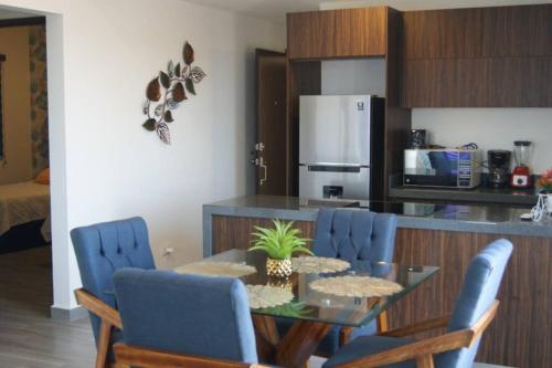 a kitchen with a dining table and blue chairs at Nuevo departamento, excelente ubicación y muchas amenidades in Mazatlán