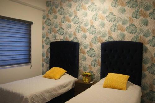 a bedroom with two beds with yellow pillows on them at Nuevo departamento, excelente ubicación y muchas amenidades in Mazatlán