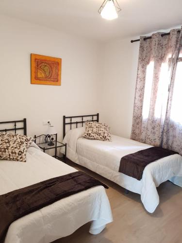 a bedroom with two beds and two windows at El Rincón de Cambados in Cambados