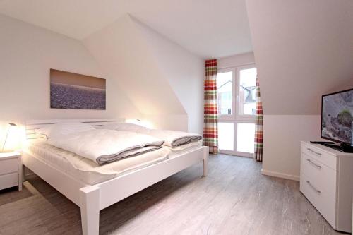 a white bedroom with a bed and a television at Merlin 3 Waldstr 20 h in Kellenhusen