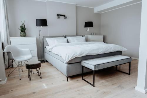 ein weißes Schlafzimmer mit einem Bett und einem Stuhl in der Unterkunft 2-Zimmer City Apartment 57m² mit King Size Bett und Küche in Münster