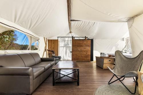 - un salon avec un canapé et une table dans une tente dans l'établissement Under Canvas Great Smoky Mountains, à Pigeon Forge