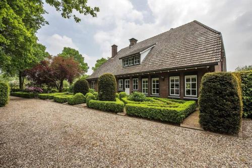 une maison avec des haies devant elle dans l'établissement Karibu Het Voorhuis 2 tot 6 persoons luxe slaapkamers met een mooie woonkeuken, à Daarle