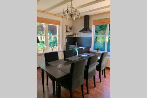 een eetkamer met een zwarte tafel en stoelen bij Karibu Het Voorhuis 2 tot 6 persoons luxe slaapkamers met een mooie woonkeuken in Daarle