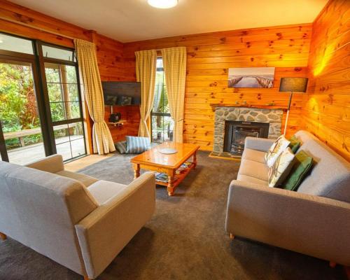 BarrytownにあるPaparoa Beach Hideaway with Hot Tubの2つのソファと暖炉のあるリビングルーム