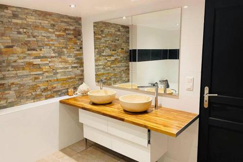 two bowls on a wooden counter in a bathroom at Charmante maison avec jacuzzi in Montazels