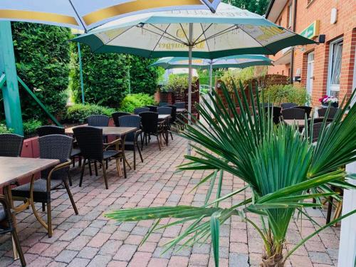 a patio with tables and chairs and umbrellas at Hotel Restaurant Byblos in Nordwalde