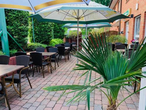 eine Terrasse mit Tischen, Stühlen und Sonnenschirmen in der Unterkunft Hotel Restaurant Byblos in Nordwalde