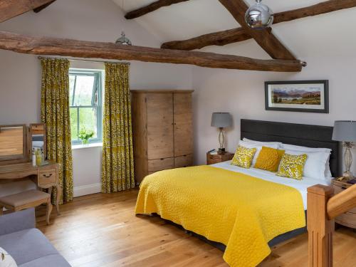 a bedroom with a yellow bed and a window at High View Barn in Carnforth