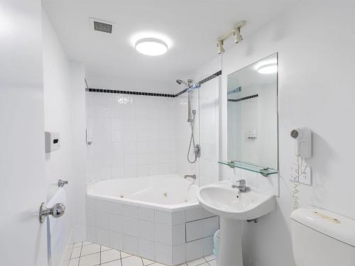 a white bathroom with a tub and a sink at The Landmark 211 Resort Style holiday with pool games room and restaurant in Nelson Bay