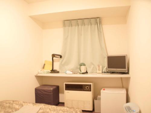 a room with a bed and a window with a computer on a shelf at Business Hotel Chateau Est Takamatsu in Takamatsu