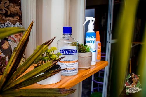 a shelf with two bottles of cleaner and a plant at Aloha Oe Itaguá in Ubatuba