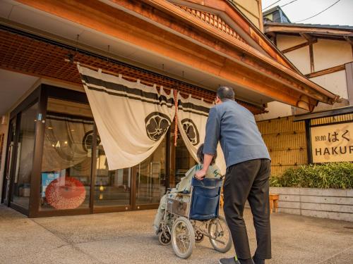 a man pushing a stroller in front of a store at Ryokan Hakura in Yamanouchi