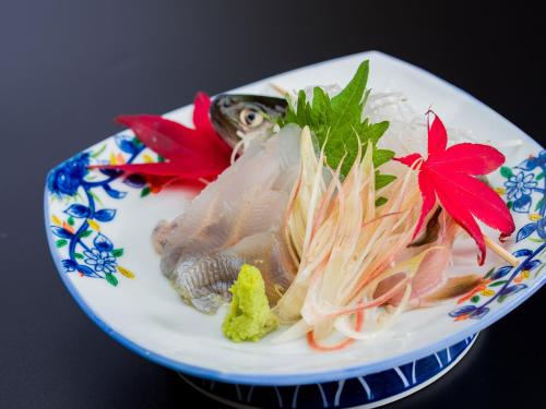 un plato de comida con pescado y verduras. en Ryokan Hakura, en Yamanouchi