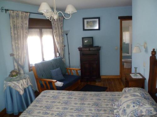 a bedroom with a bed and a chair and a television at Artesano I y III in Navarredonda de Gredos
