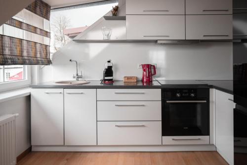 a kitchen with white cabinets and a black appliance at Laurentroom Oldtown in Ukmergė