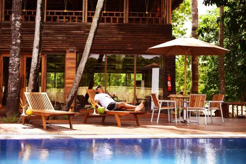 a man sitting on a chair next to a pool at De Foret in Havelock Island