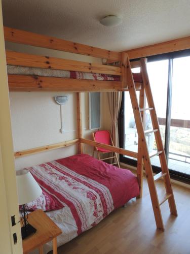 a bedroom with a bunk bed with a ladder at F2 Le Corbier aux pieds des pistes, commerces et esf in Le Corbier