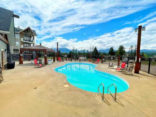 a swimming pool in a yard with chairs and a building at Sable Ridge Condos by FantasticStay in Radium Hot Springs