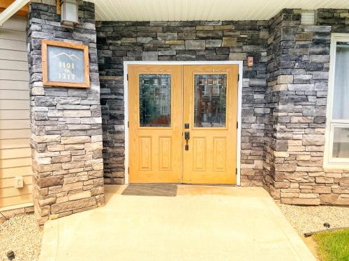 a house with a yellow door with a stone wall at Sable Ridge Condos by FantasticStay in Radium Hot Springs