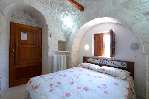 1 dormitorio con 1 cama y puerta de madera en Agriturismo con Trullo, en Alberobello