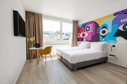 a hotel room with a bed and a large window at B&B HOTEL St Gallen in St. Gallen
