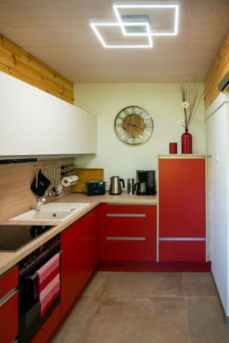 a kitchen with red cabinets and a clock on the wall at Wendenkoenighof in Kolonie